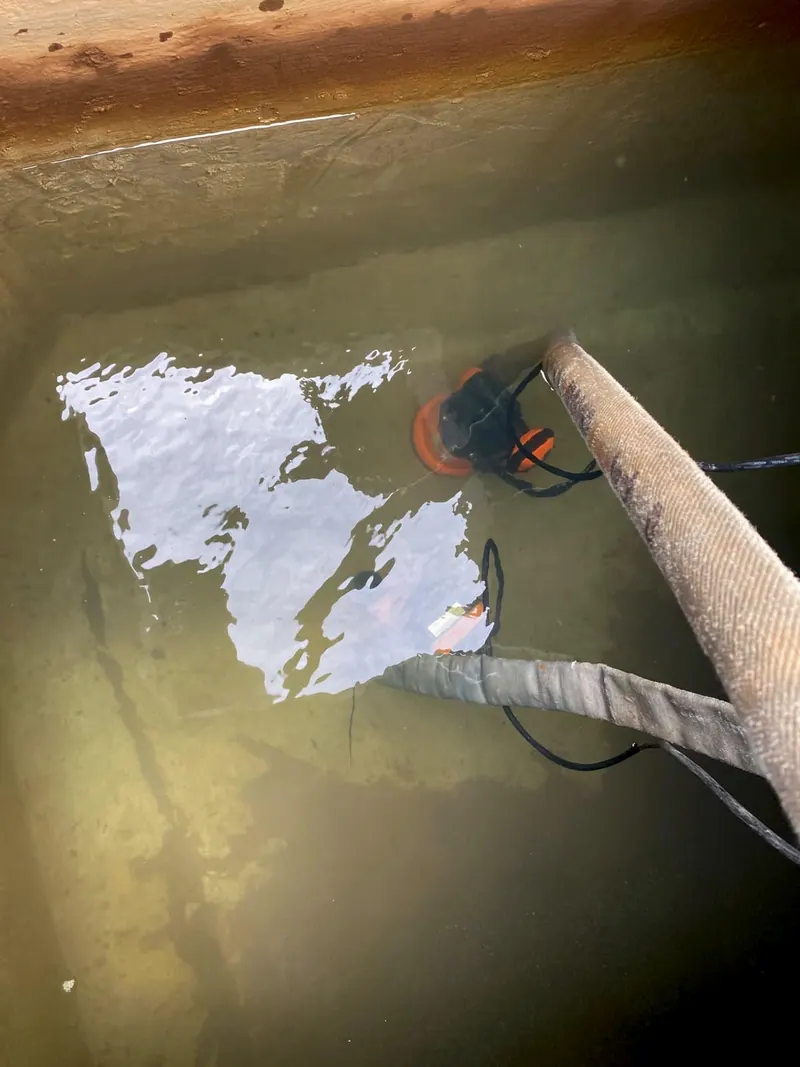 Bomba submersa na água suja do fundo da cisterna, antes da limpeza